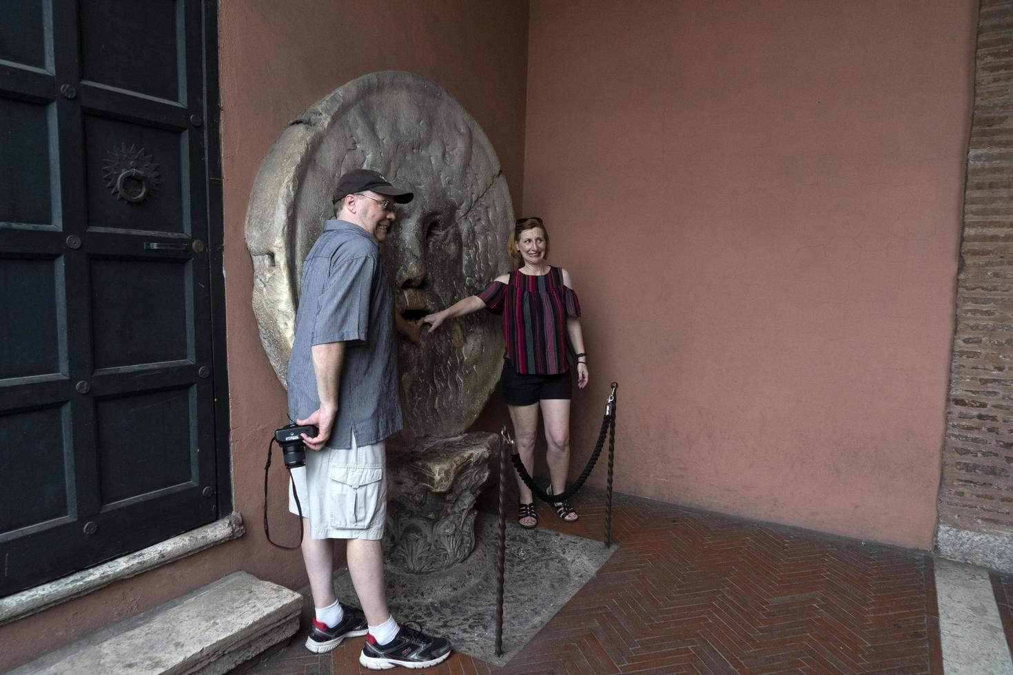 ROME, ITALY - JUNE 15 2019 - Tourist testing the mouth of truth mask photo