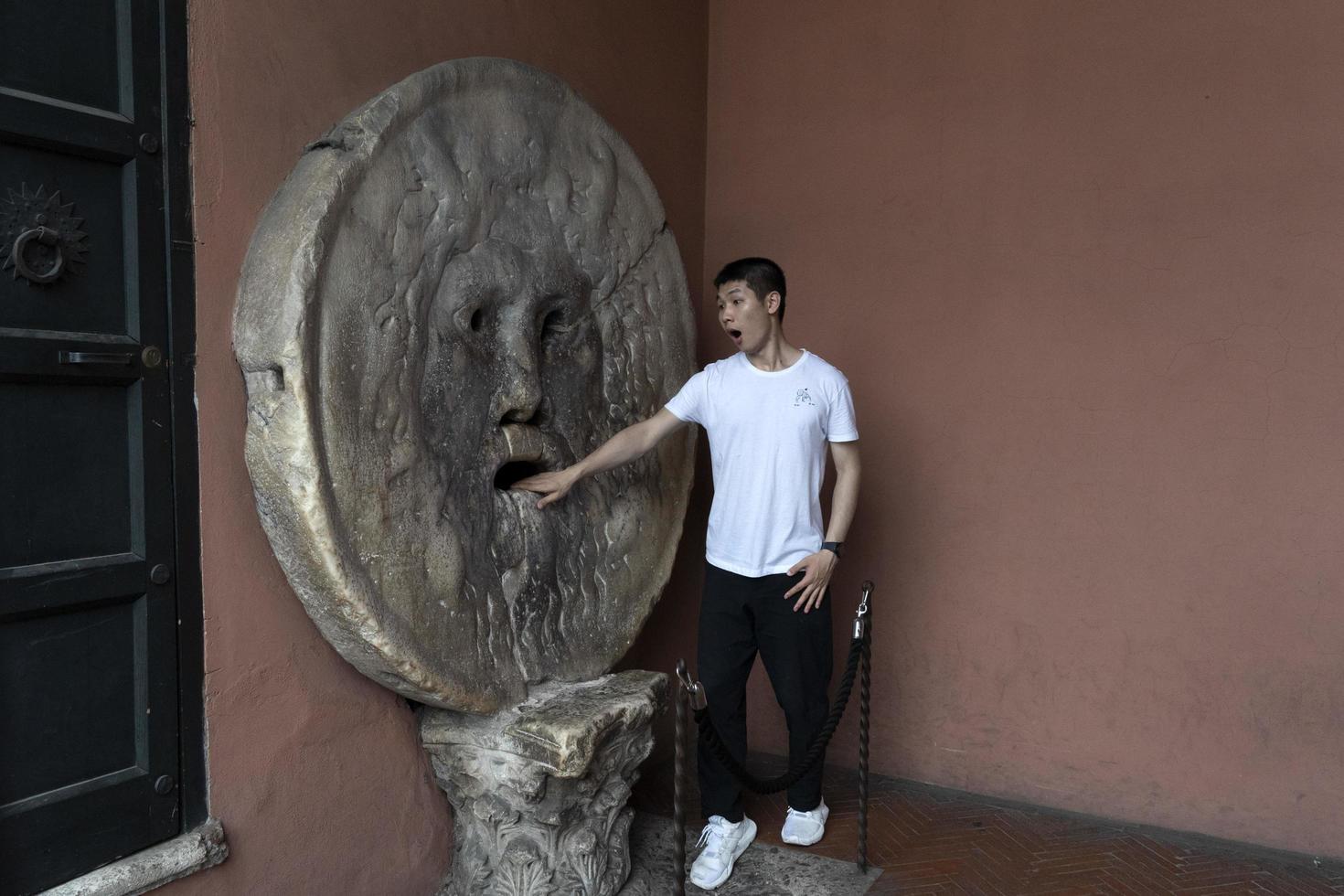 ROME, ITALY - JUNE 15 2019 - Tourist testing the mouth of truth mask photo