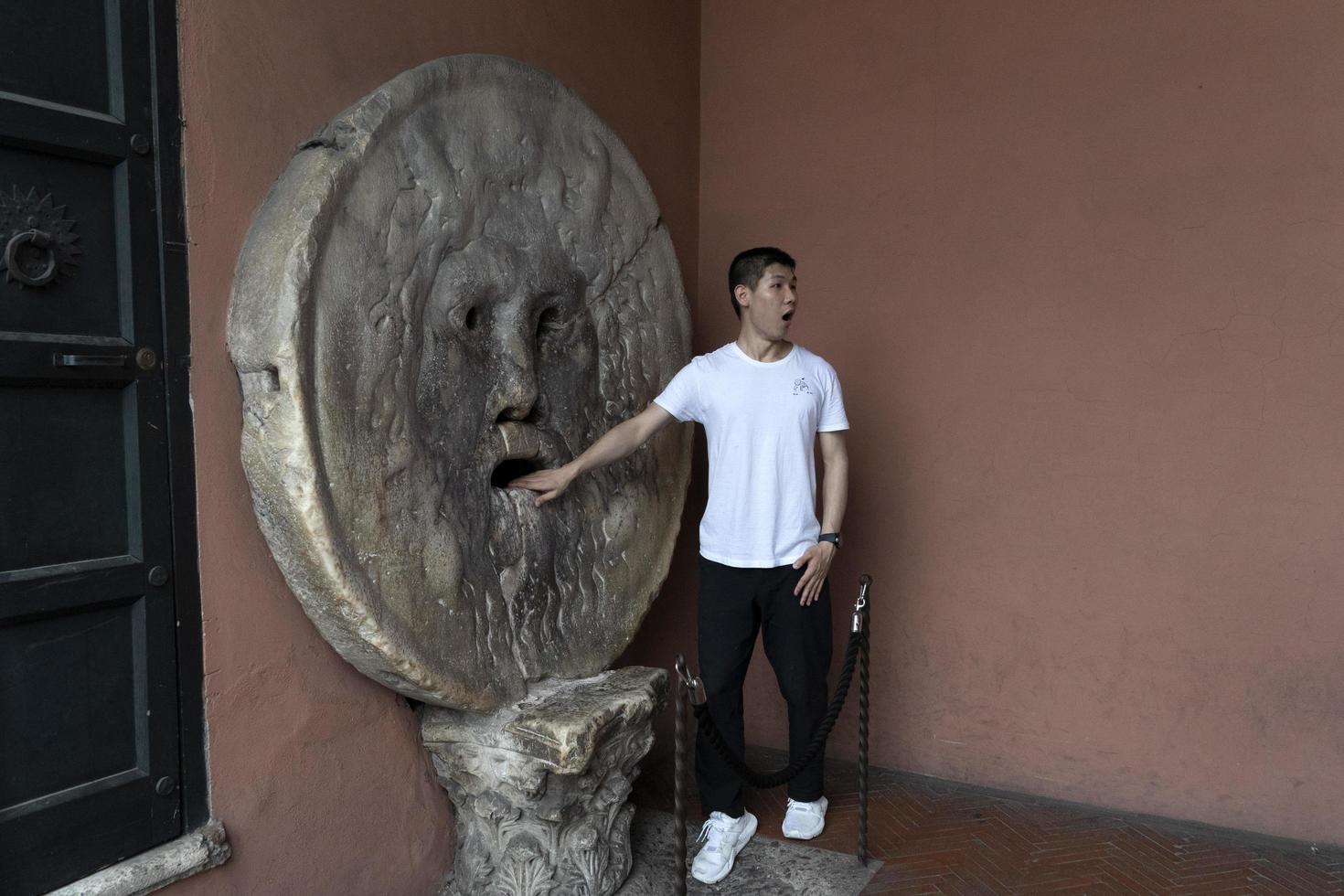 ROME, ITALY - JUNE 15 2019 - Tourist testing the mouth of truth mask photo