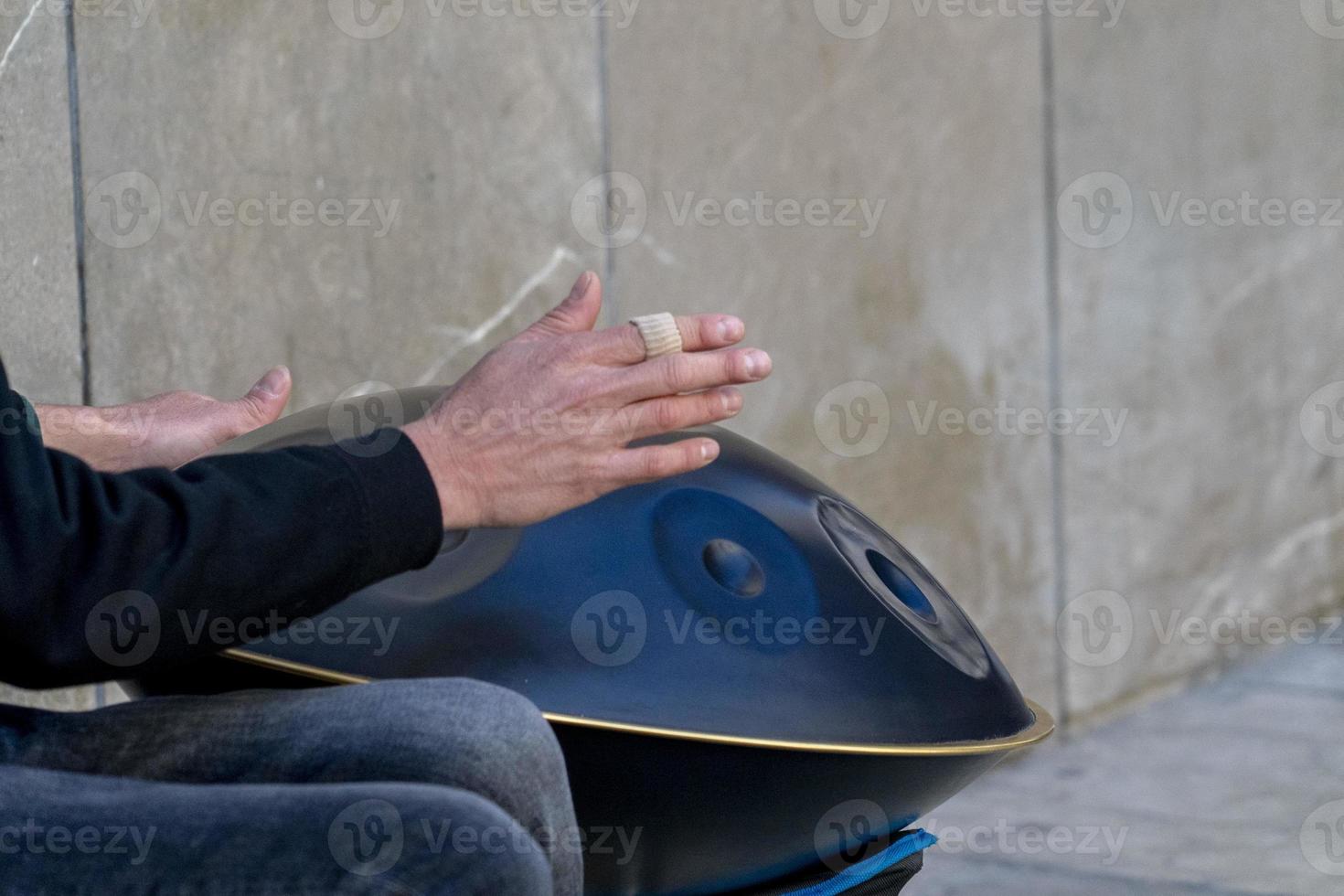 artista callejero tocando el tambor de metal colgado foto