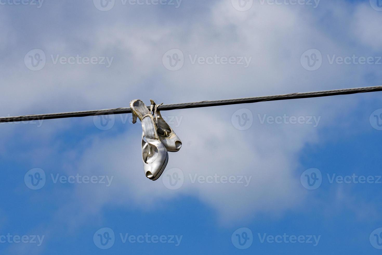 Woman female shoes hanging on wire cable photo