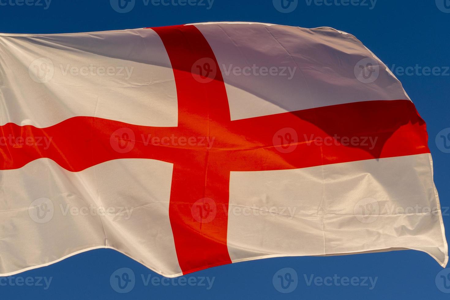 waving english flag red cross on white isolated on blue photo