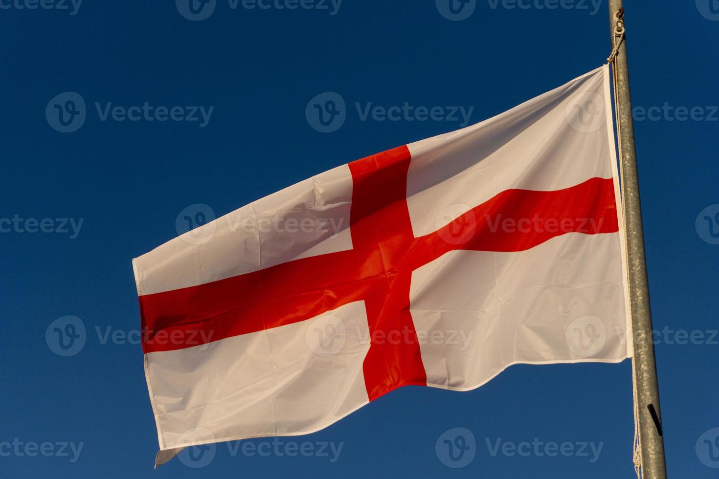 waving english flag red cross on white isolated on blue photo