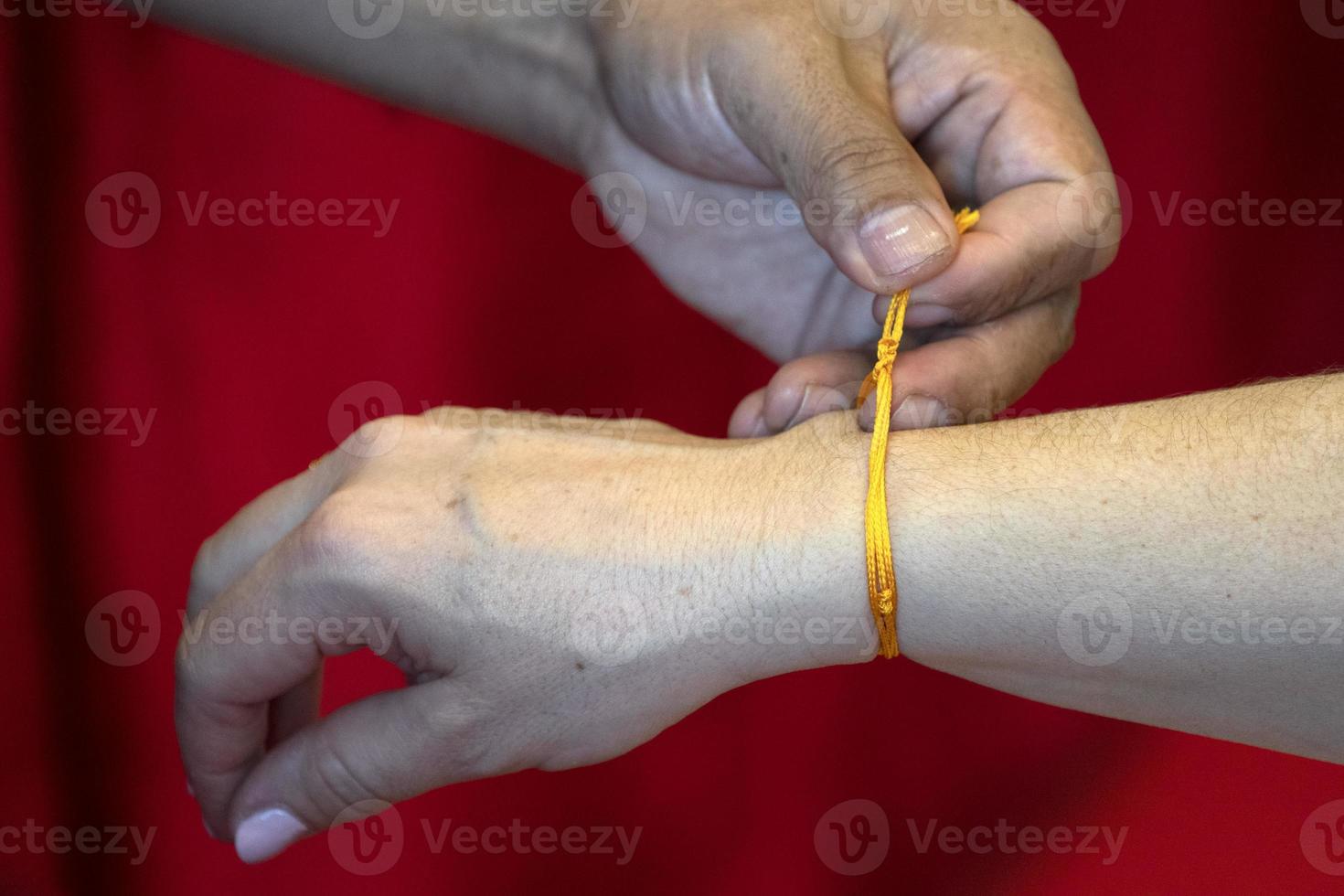 Tibetan monk while putting bracelet on buddihst hand photo