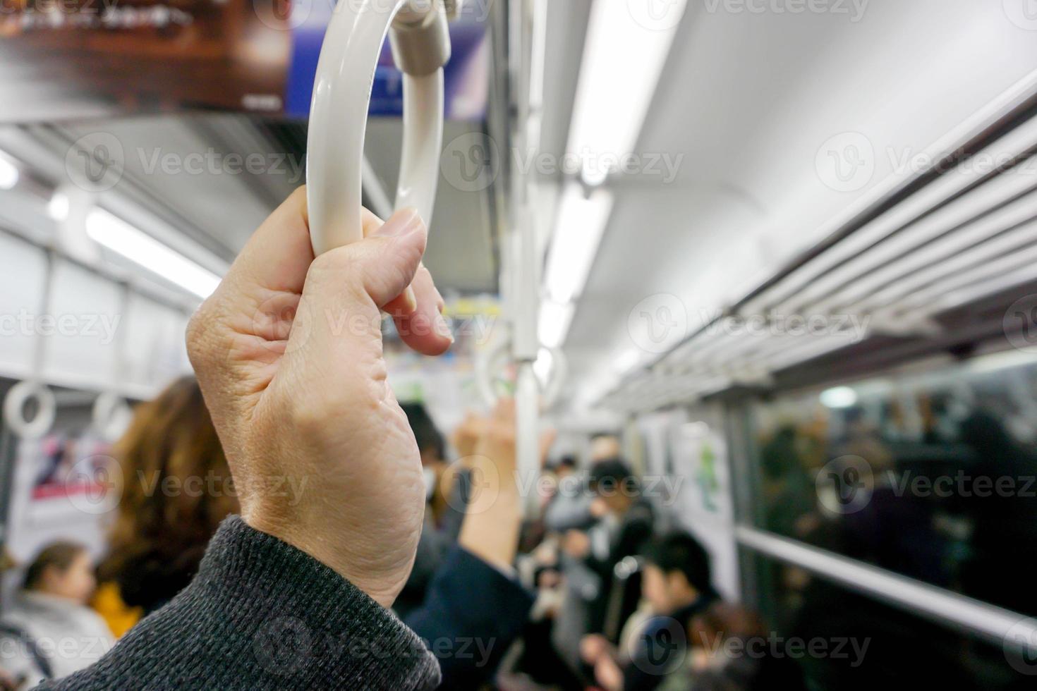 Closeup hand of human holding handle loop in a subway morning and blurry background. photo