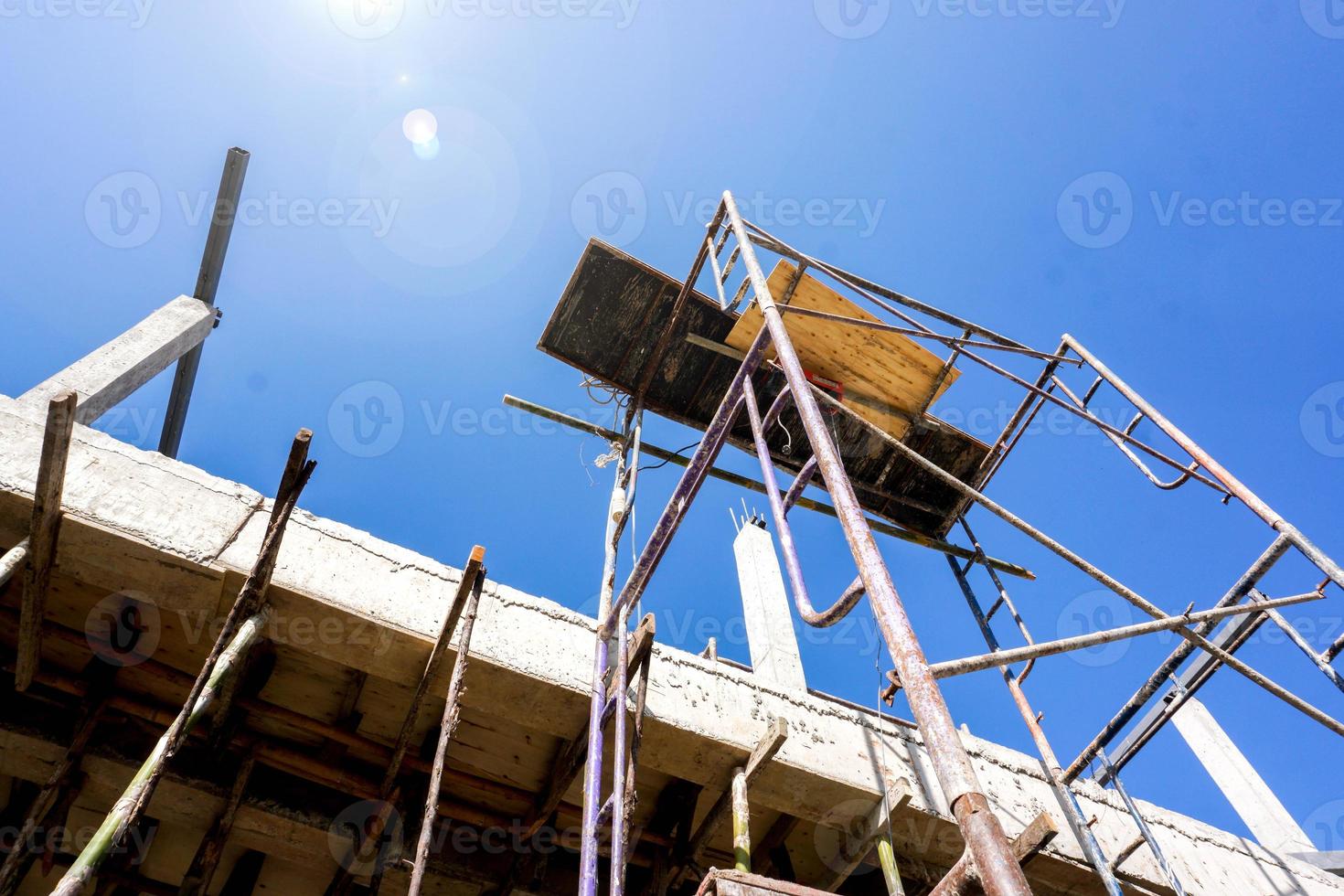 Look up view of Construction site scaffolding at home construction site with sun flare and blue sky background. photo