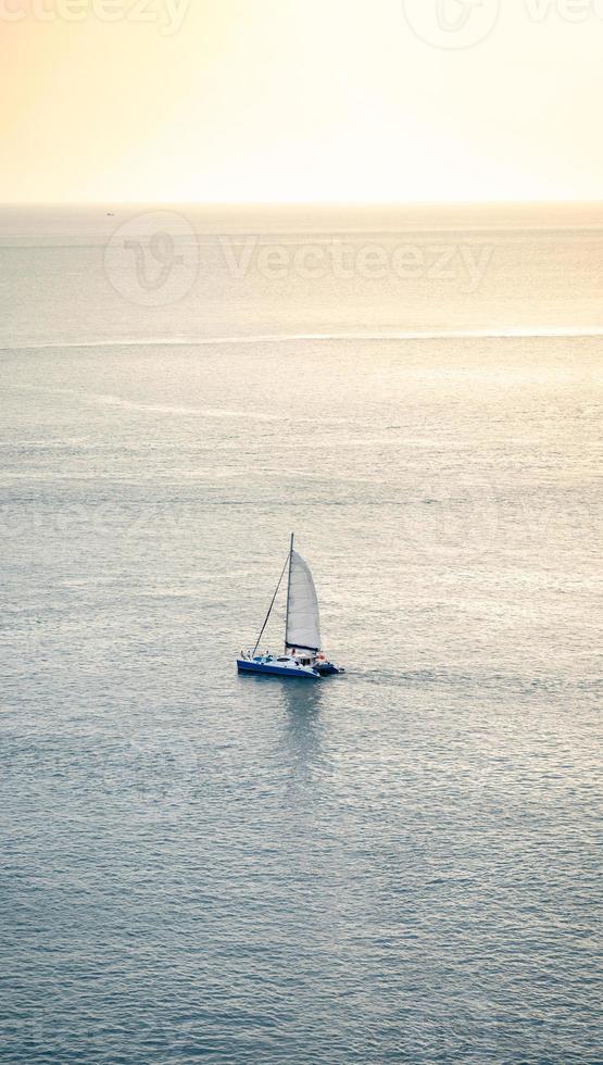 minimal Sailboat Yacht is saling on the calm sea, shoot this image from above of the mountain Phrom Thep Cape, Phuket Thailand with Tele lens. photo