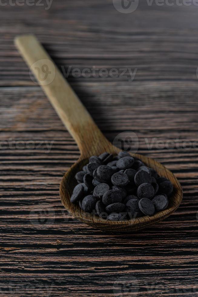 Melt chocolate buttons on a wooden spoon on a rustic background photo