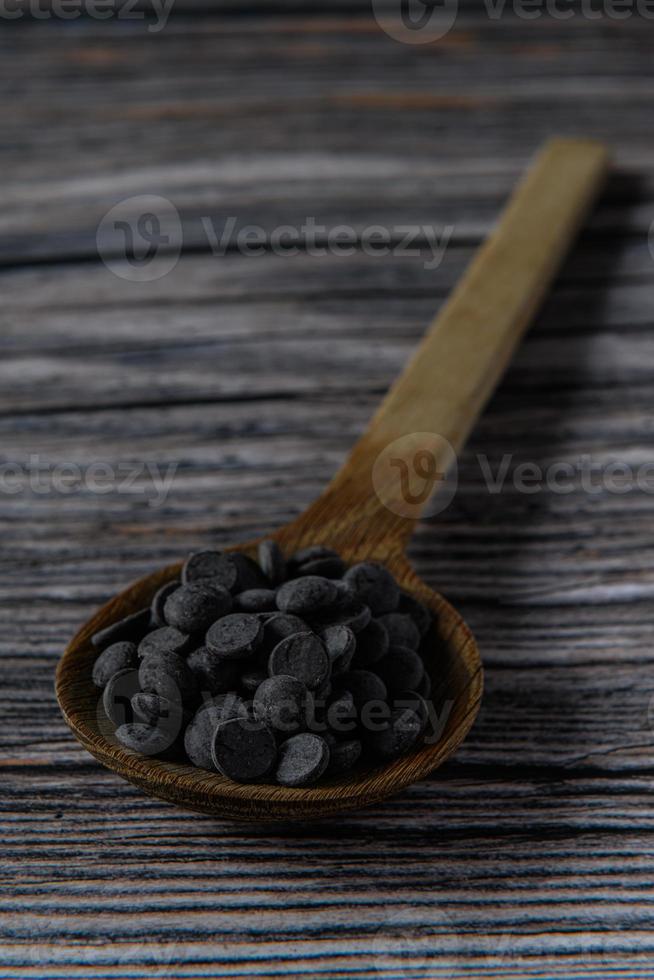 Melt chocolate buttons on a wooden spoon on a rustic background photo