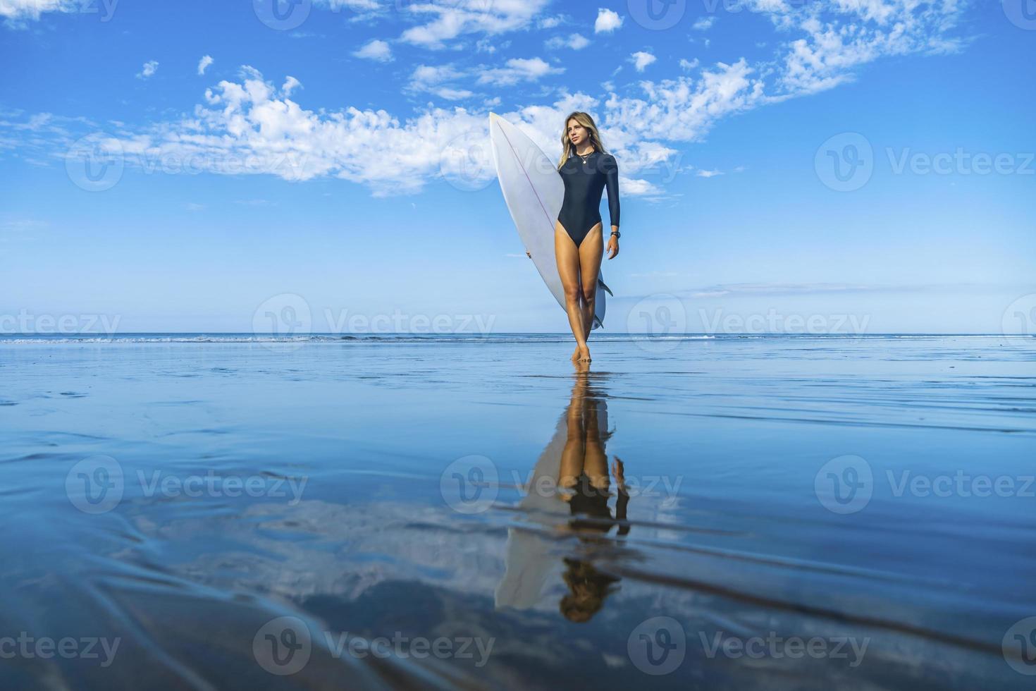 Young and athletic woman with her surfboard on the beach photo