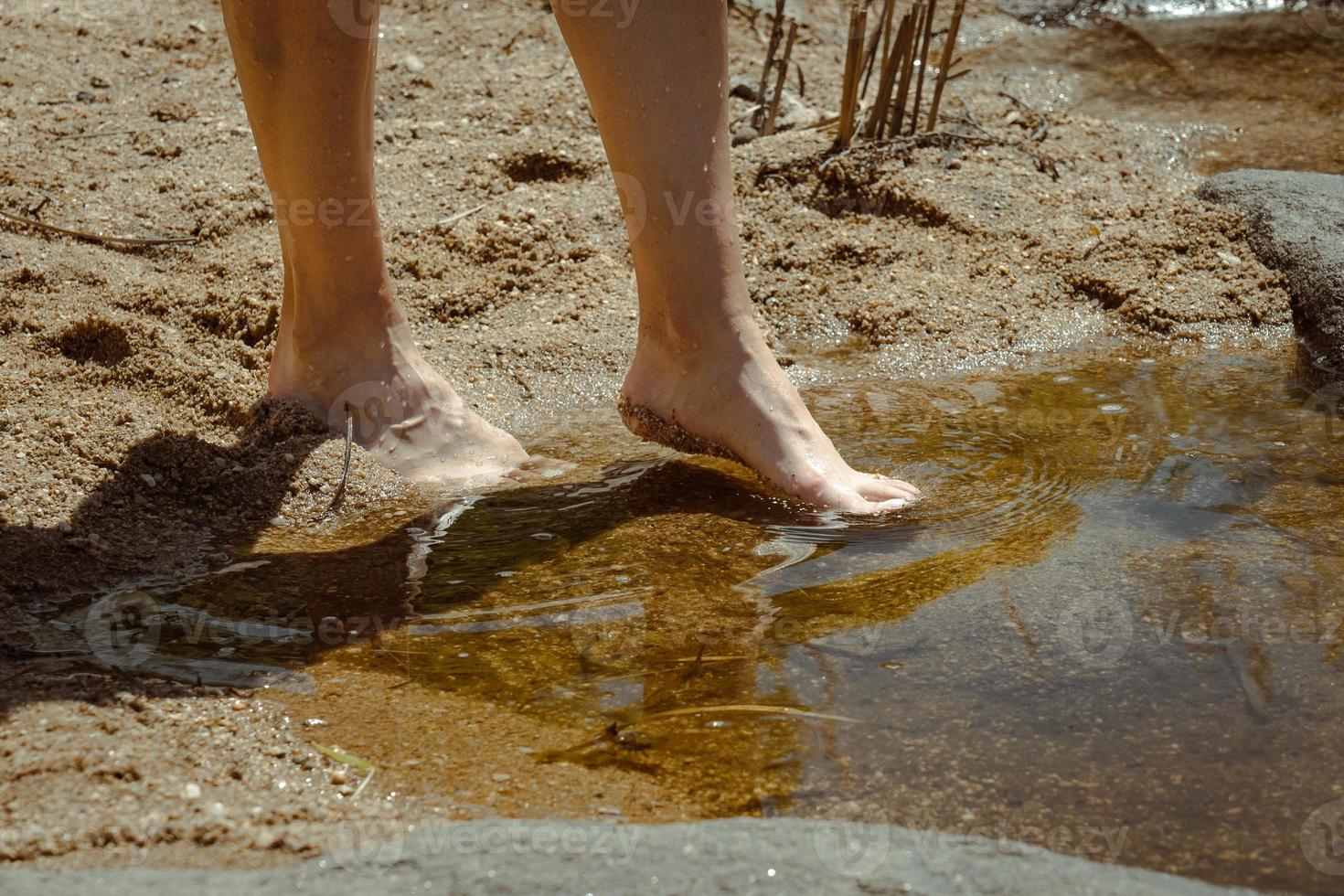 detalle de los pies de una mujer sintiendo el agua fresca del río. foto