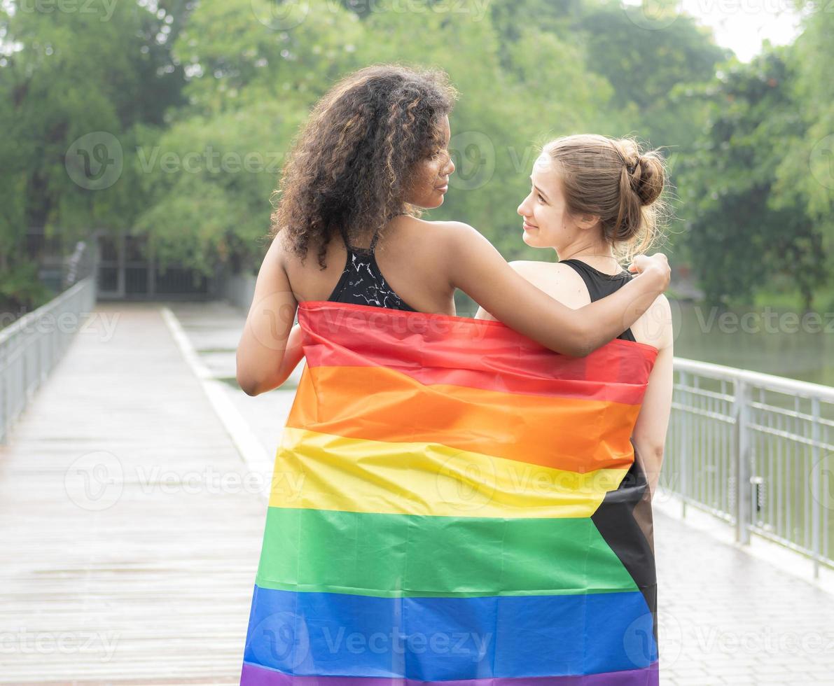 Two lesbian people friendship with rainbow pride flag. Cheerful gay person having fun together with equality respect to love and freedom lifestyle. Diversity of young homosexual couple, LGBTQ rights. photo