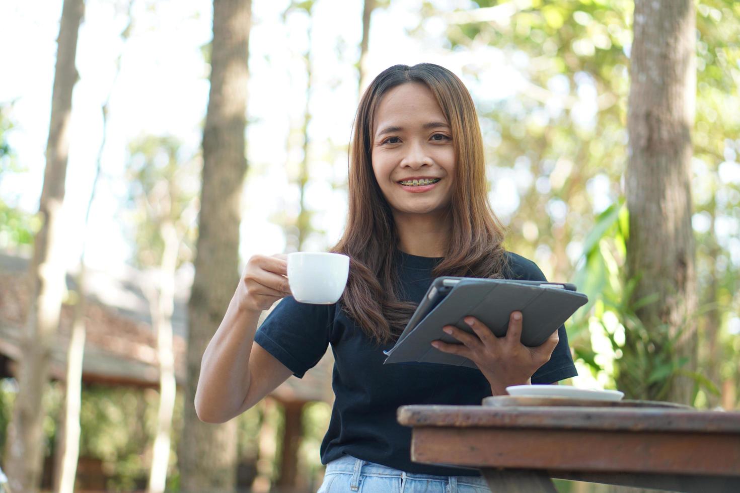 Asian women are happy to sit and work in a coffee shop. There are green trees surrounded by nature. photo