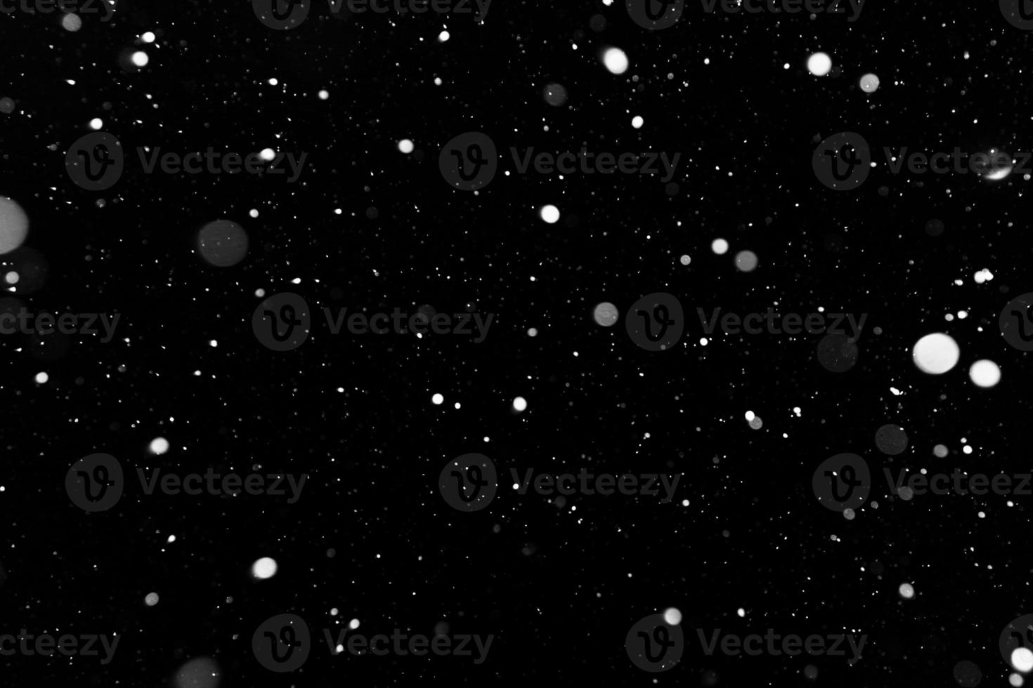 Bokeh white snow on a black night background photo