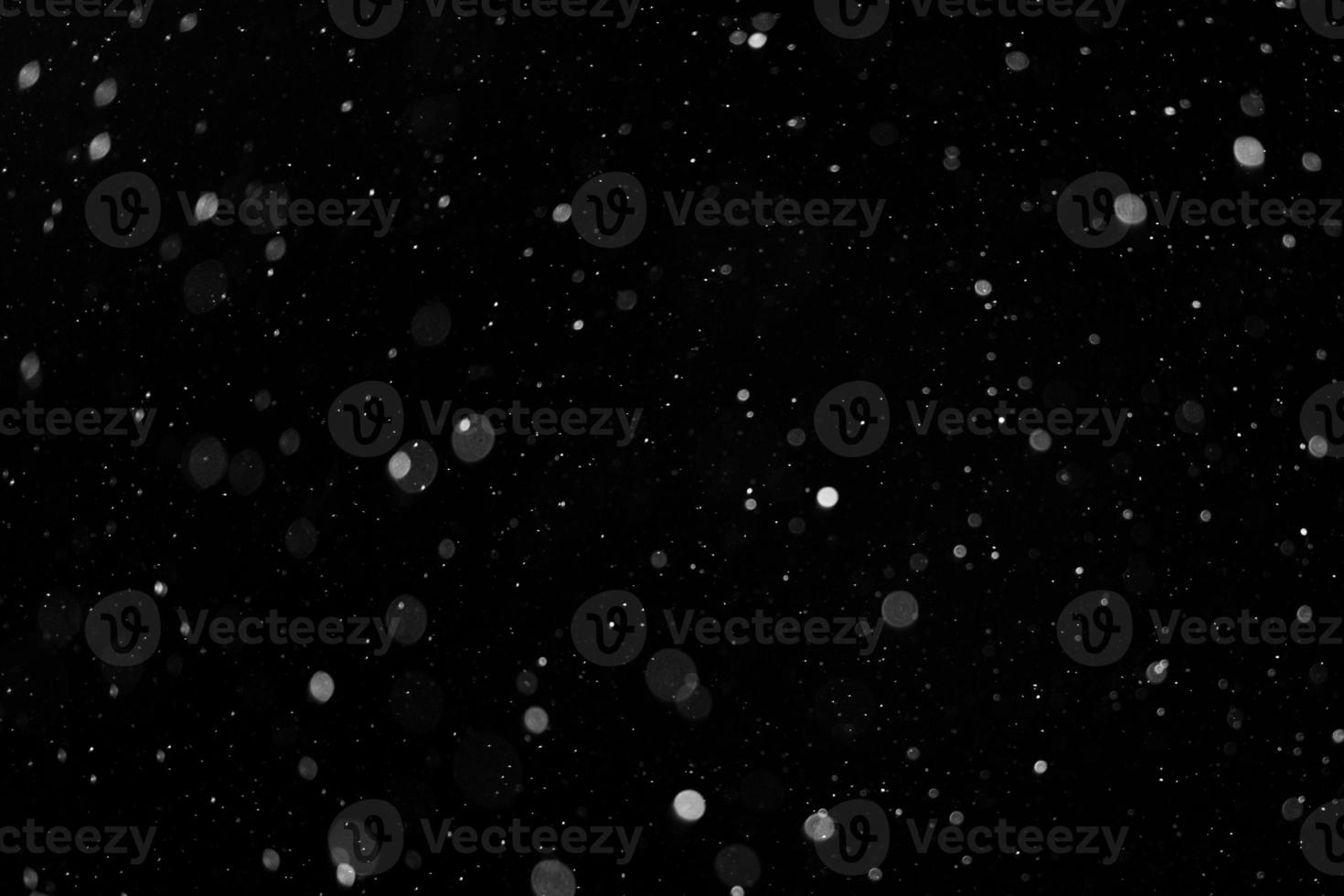 a bokeh of white snow on a black background photo