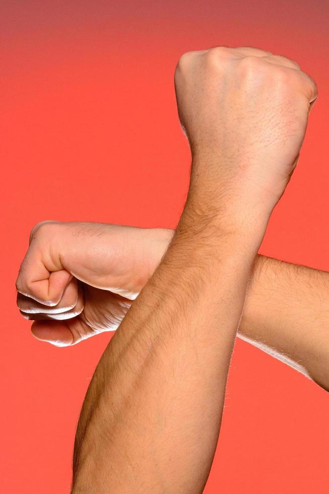 Human hand that squeezed fingers into a fist, symbolizing hatred and resistance, isolated on a red background photo