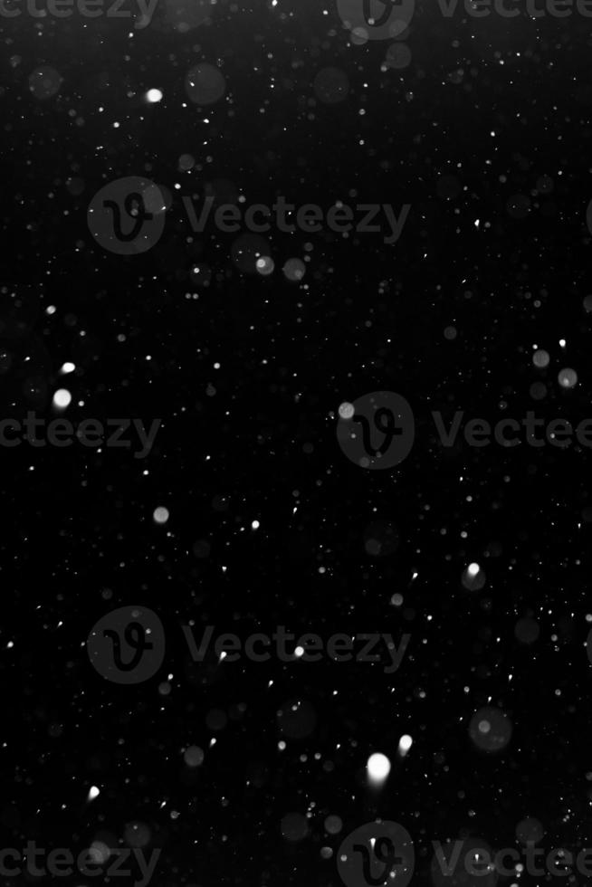 a bokeh of white snow on a black background photo