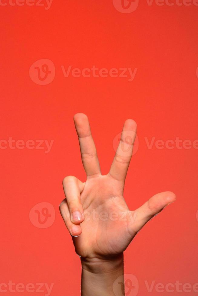 Male hand is showing three fingers isolated on red background photo