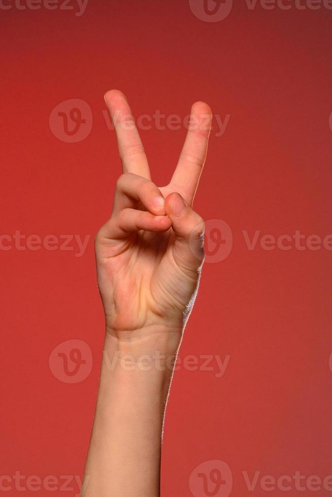 The soft hand showing the victory sign is isolated on a red background photo