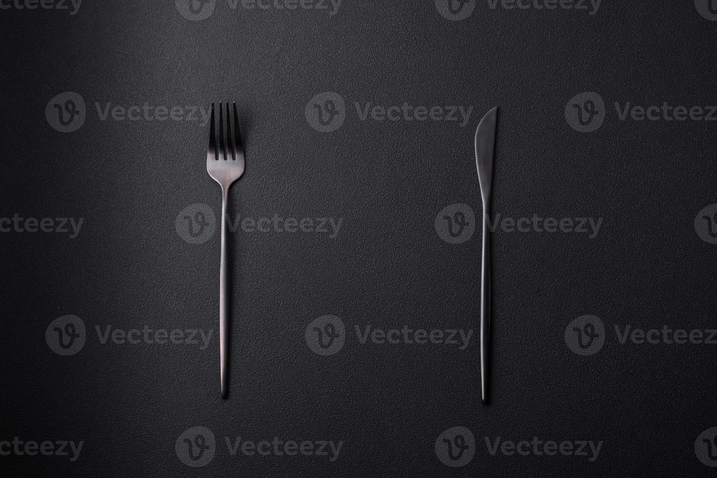 Metal kitchen knife and fork on a dark textured concrete background photo