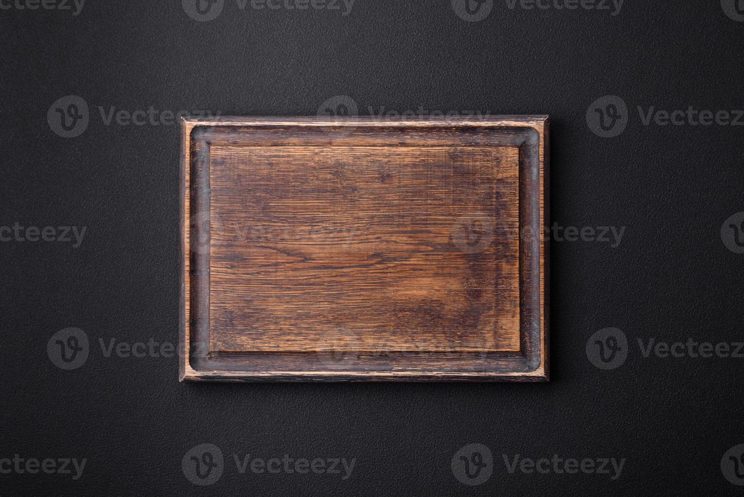 Empty wooden cutting board on dark textured concrete background photo