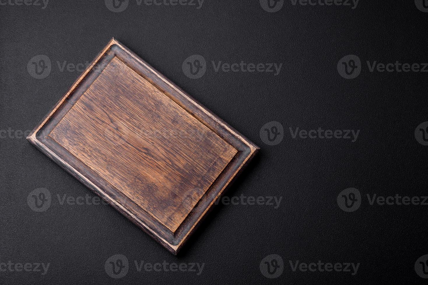Empty wooden cutting board on dark textured concrete background photo