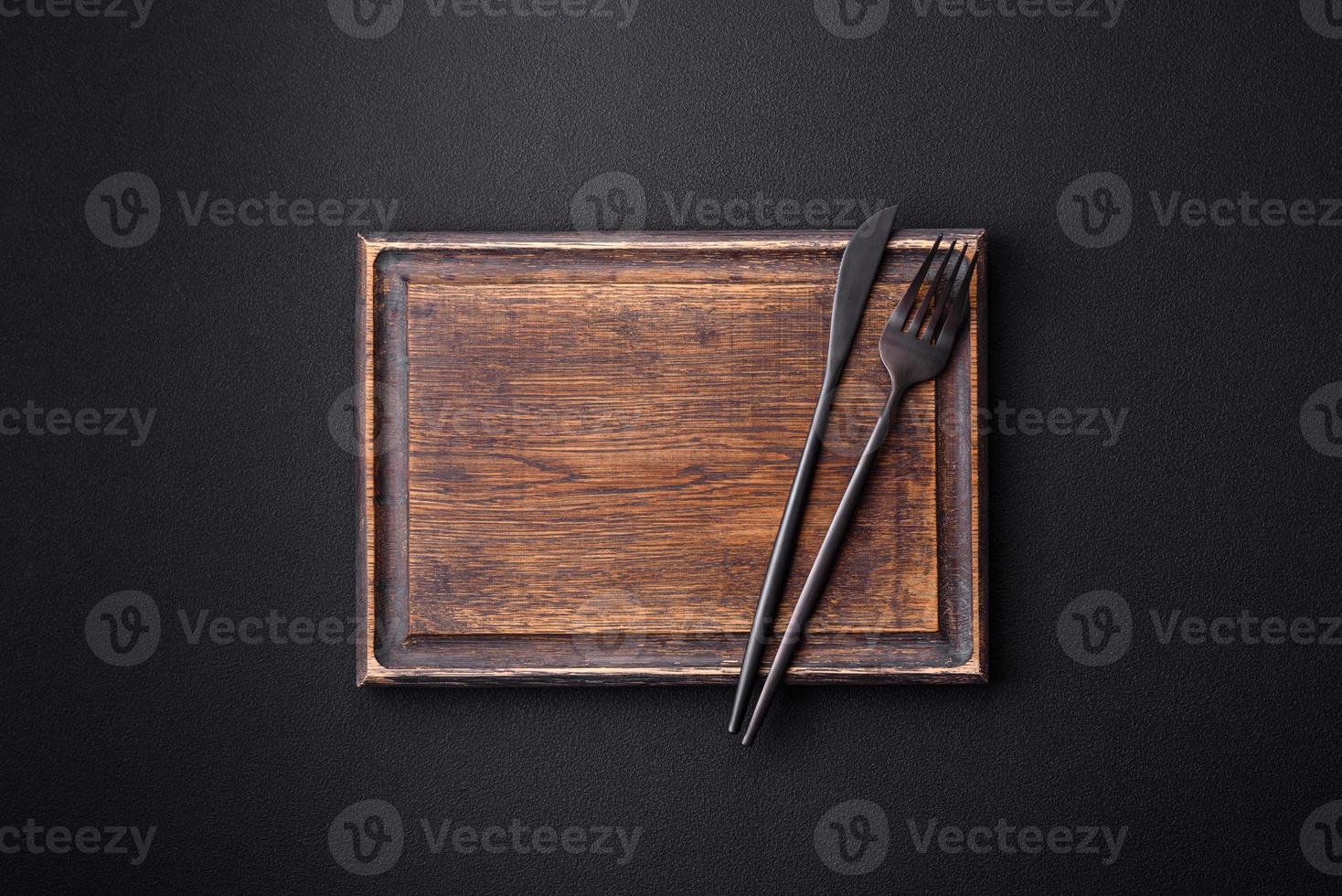 Empty wooden cutting board on dark textured concrete background photo