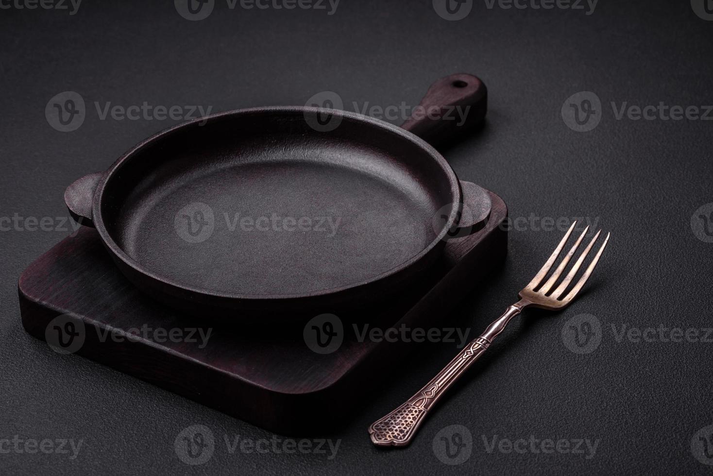 Empty round cast iron skillet on dark textured concrete background photo