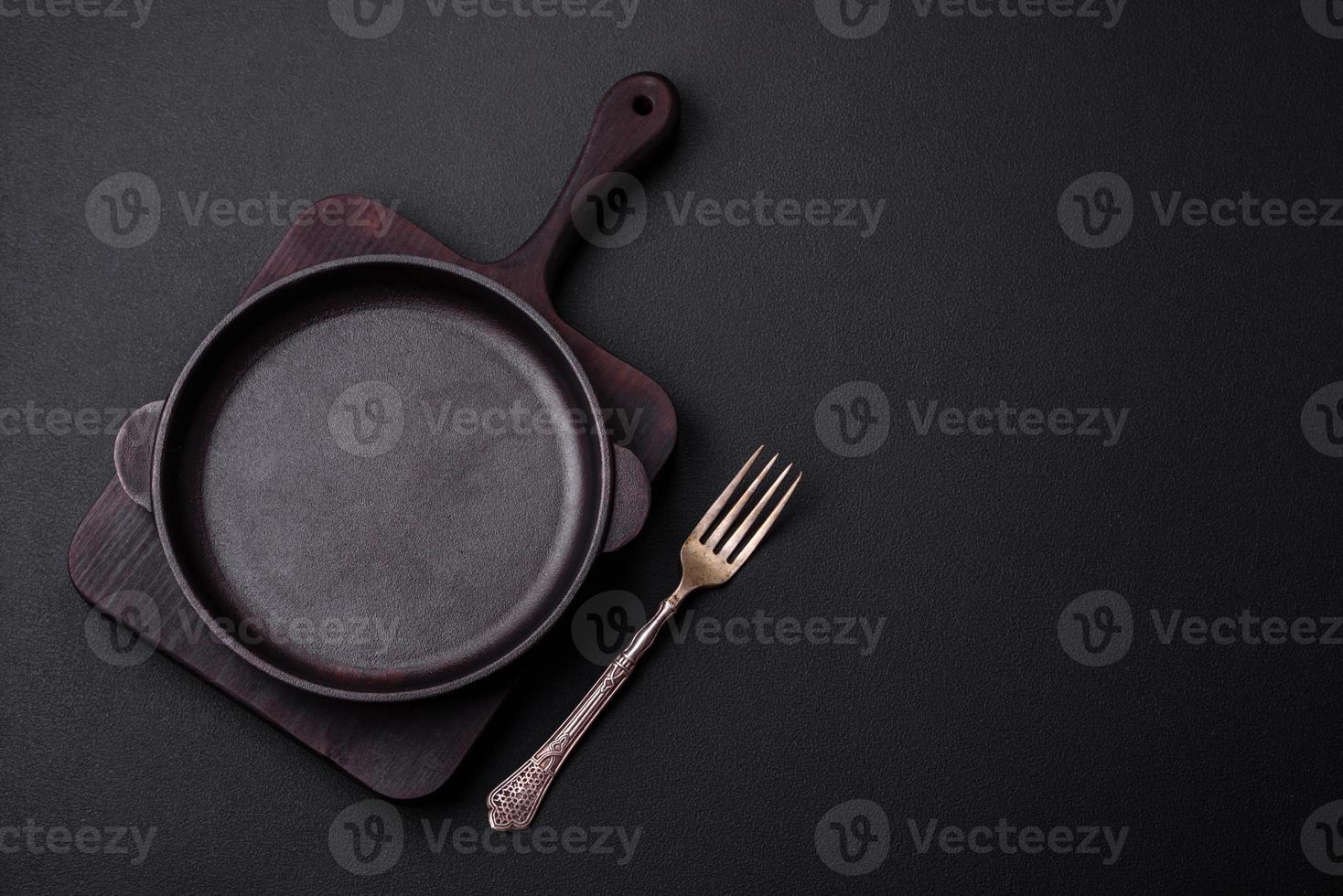 Empty round cast iron skillet on dark textured concrete background photo