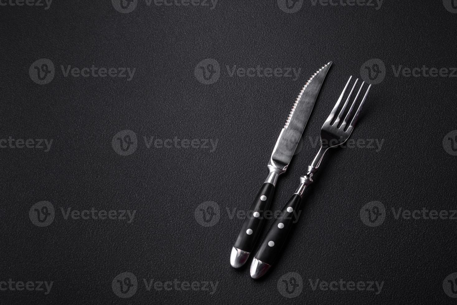 Metal kitchen knife and fork on a dark textured concrete background photo