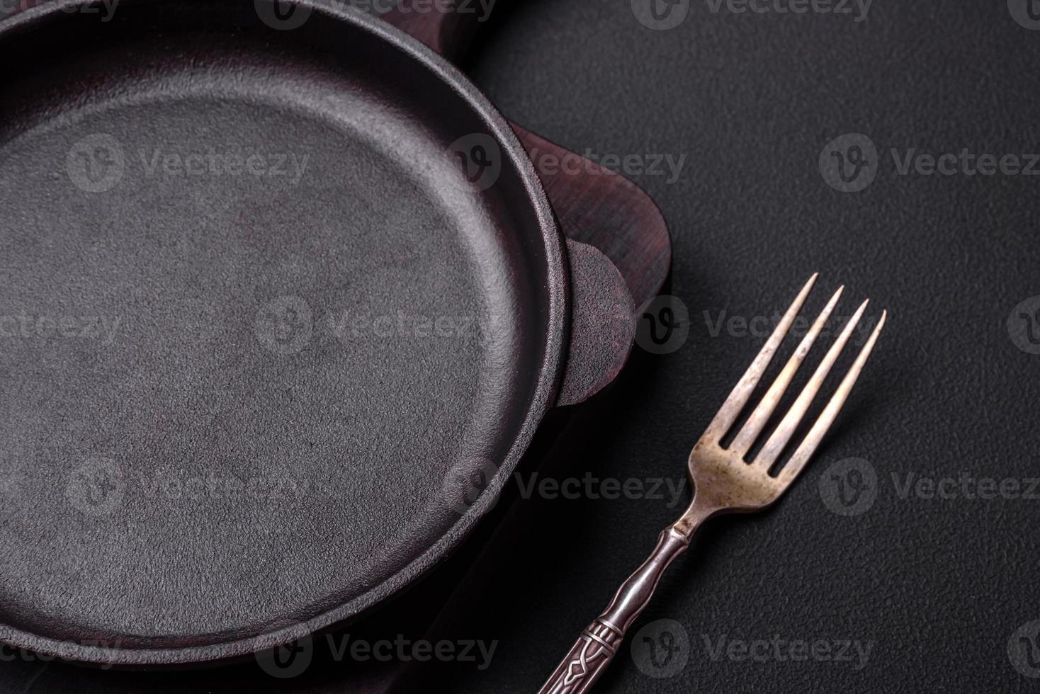 Empty round cast iron skillet on dark textured concrete background photo