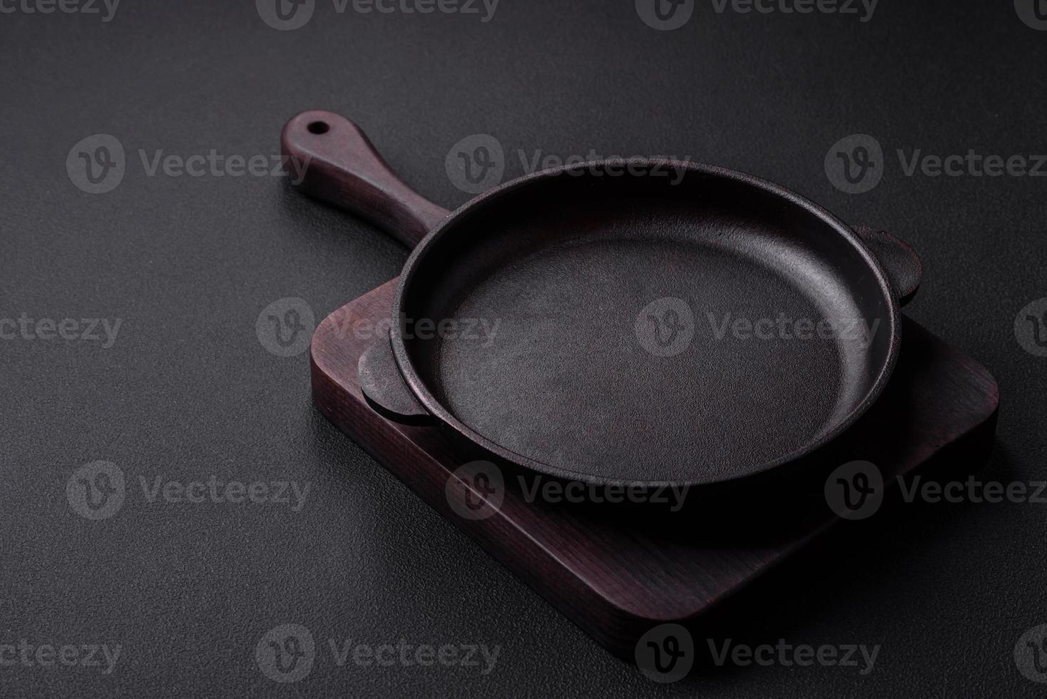 Empty round cast iron skillet on dark textured concrete background photo