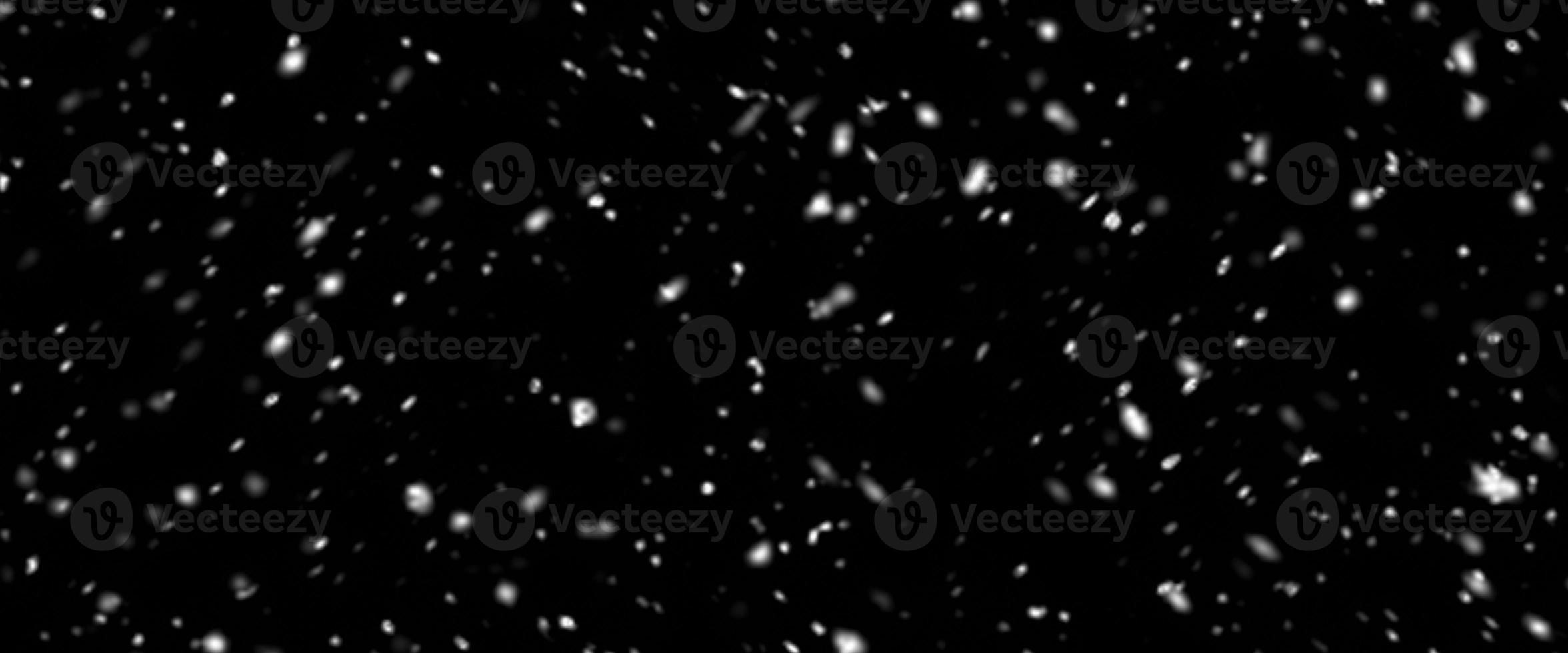 Falling snow isolated on black background. Falling snow at night. Bokeh lights on black background, flying snowflakes in the air. Winter weather. Overlay texture. photo