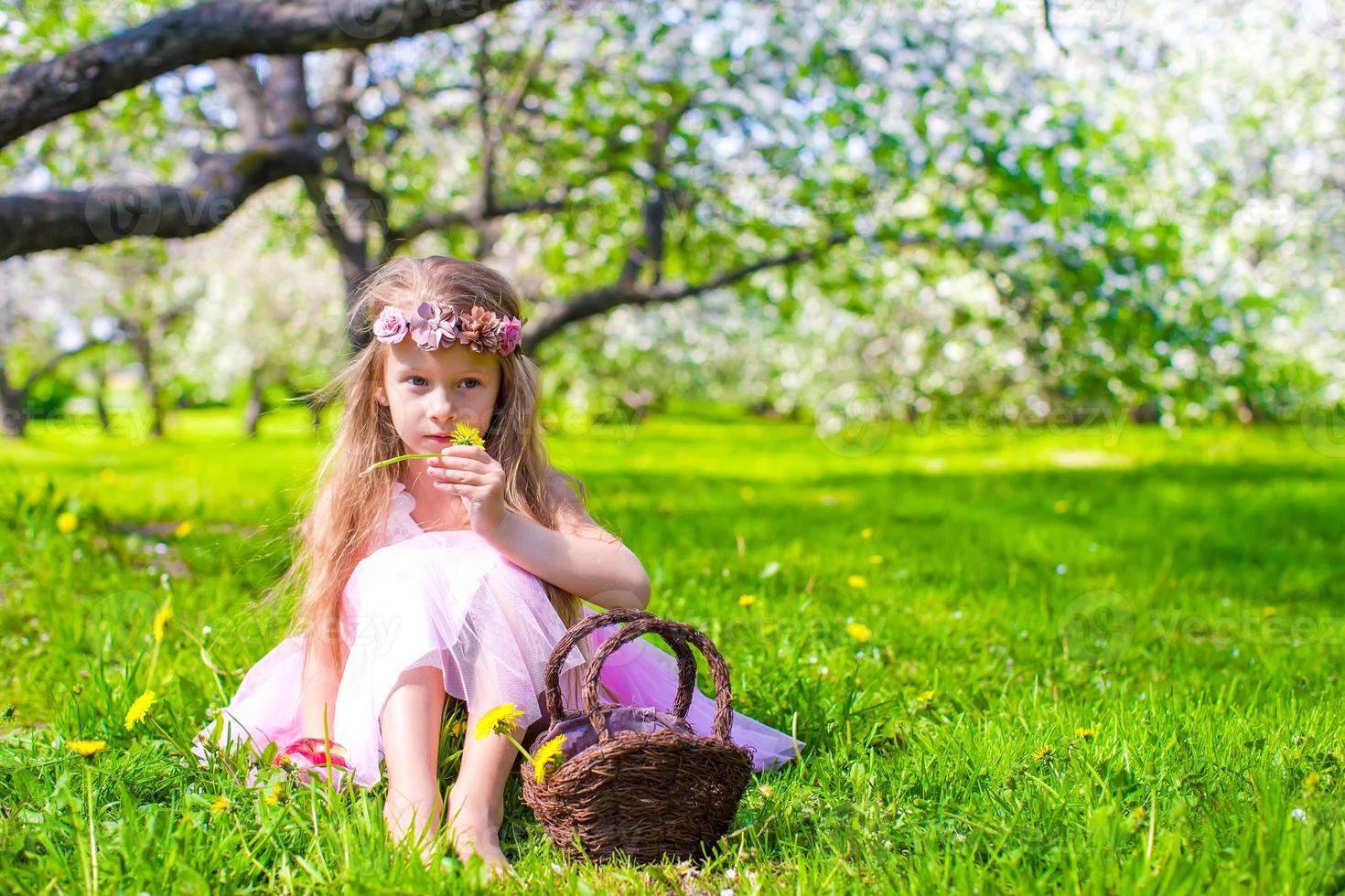 Happy little adorable girl in blossoming apple tree garden photo