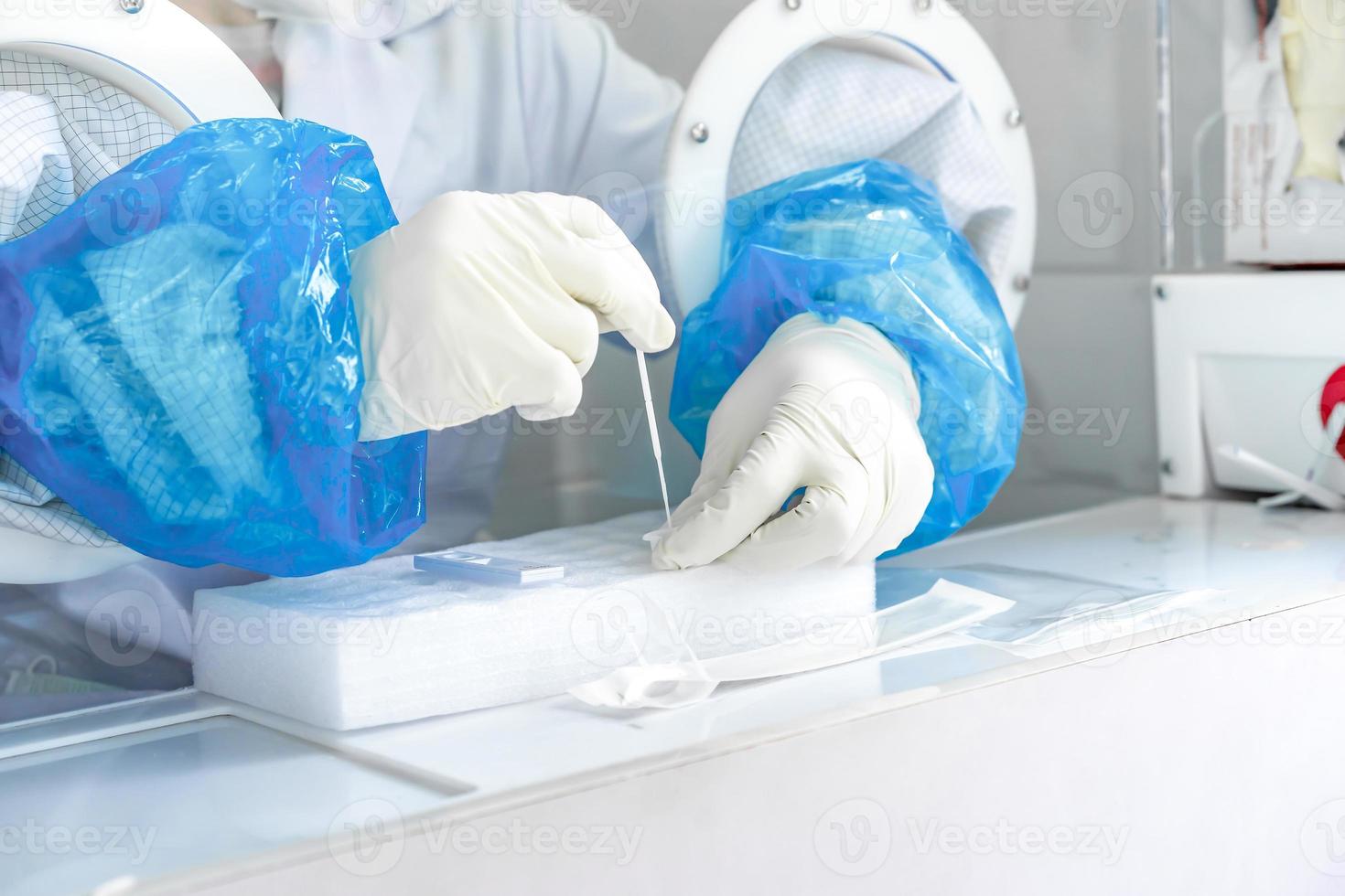 Close up to the rubber gloves on the asian medical staff is processing coronavirus or covid-19 test in the negative room pressure. photo