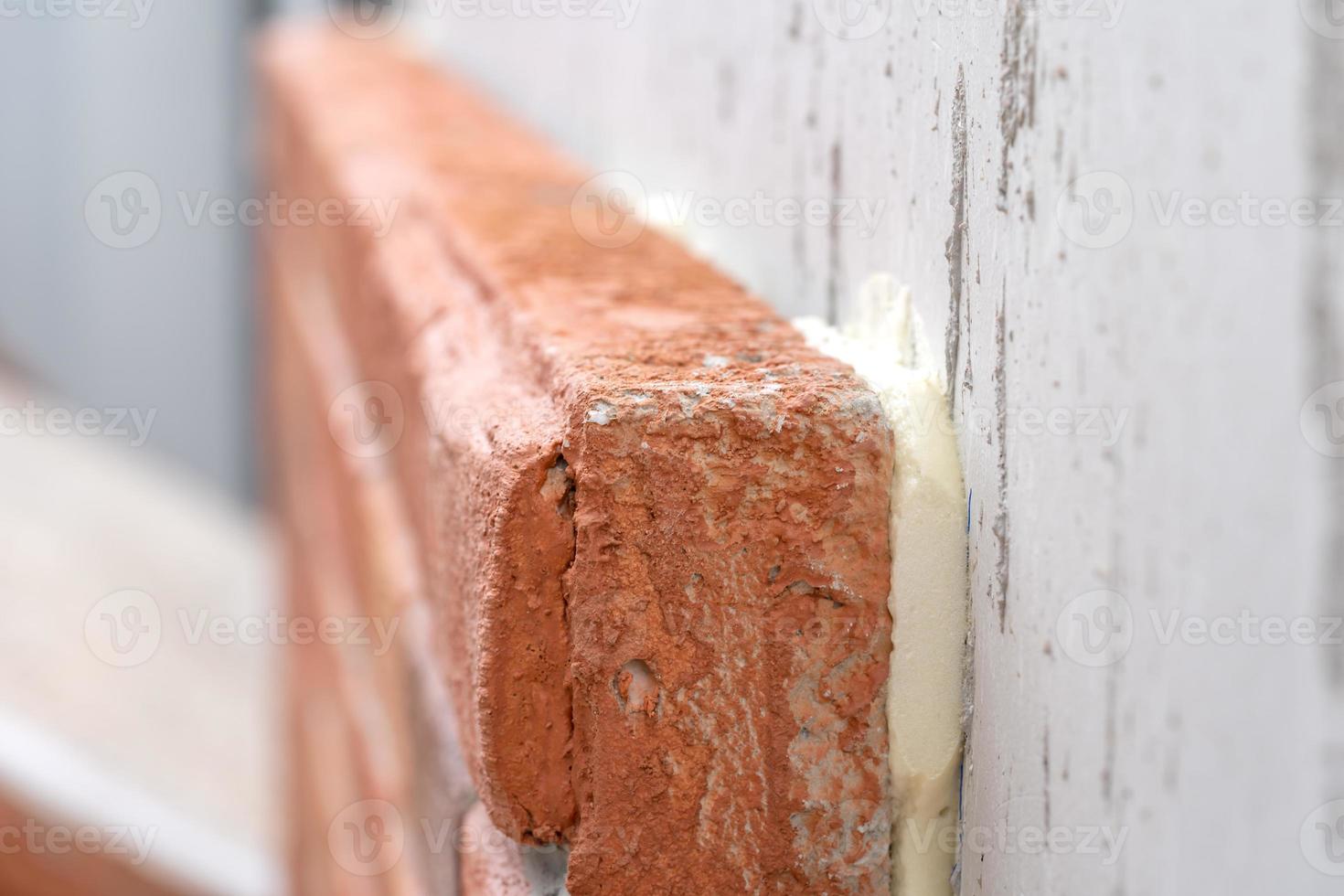 Closeup to the foam brick installation by foam glue stick on cement wall at outdoor field photo