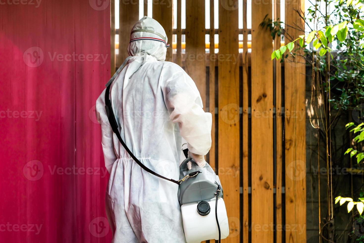 Professional technical man in prevention suit with his sterilizing machine and disinfecting water sprays in the outdoor field for purifying coronavirus COVID19 photo