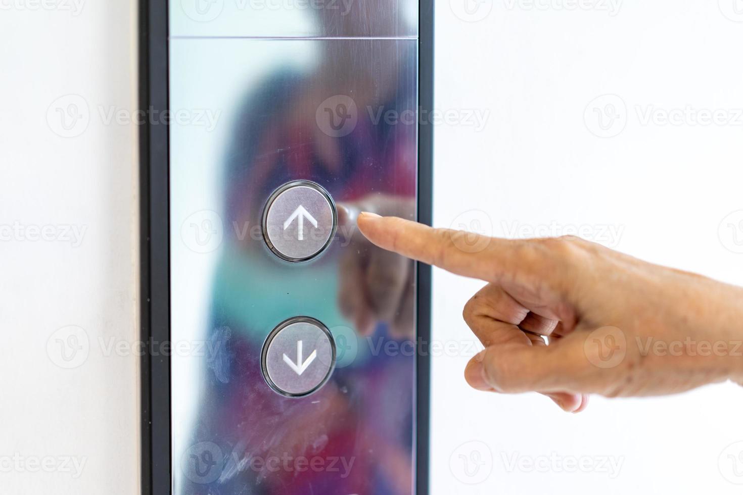 Asian old woman hand points to the button of elevator. photo