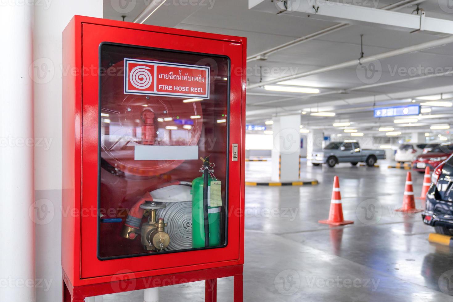 caja de carrete de manguera contra incendios en la esquina del estacionamiento de automóviles., la letra blanca en tailandés en el medio de la caja roja significa carrete de manguera contra incendios. foto