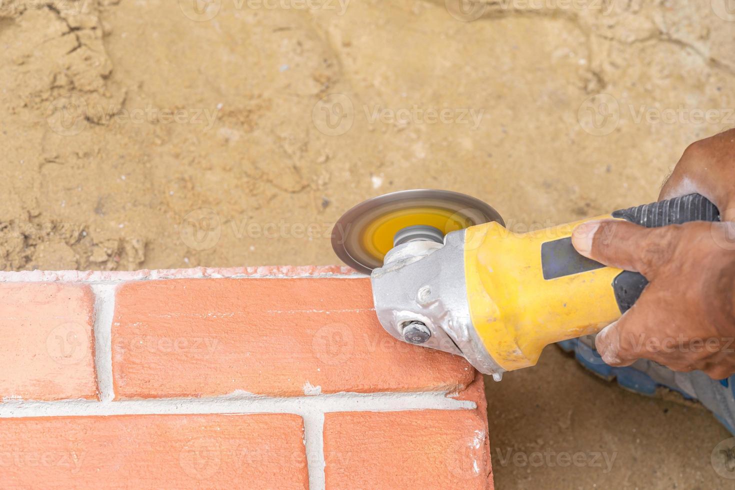 Close up worker holds Hand-Hold Sawing Machine and cuts brick foam plate board for wall installation. photo