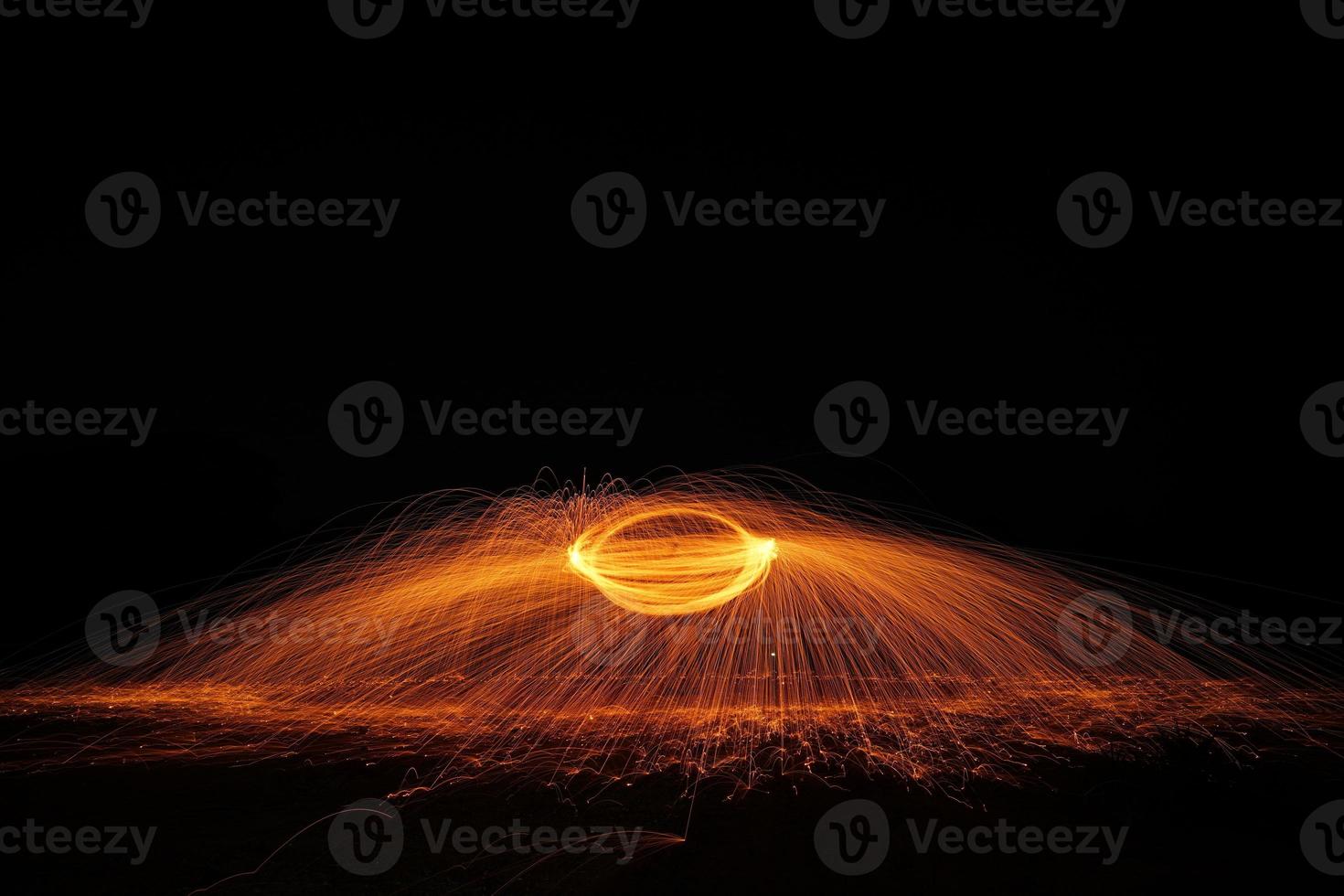 Spinning and burning Steel wool sparkle fire in the circle shape with long speed shutter shoot glowing light line to the ground. photo