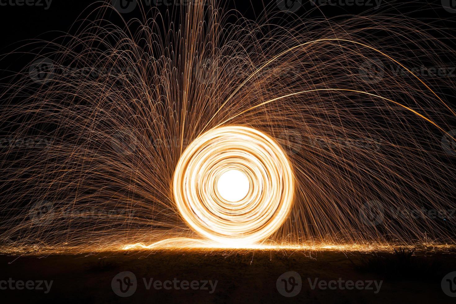 Spinning and burning Steel wool sparkle fire in the circle shape with long speed shutter shoot glowing light line to the ground. photo