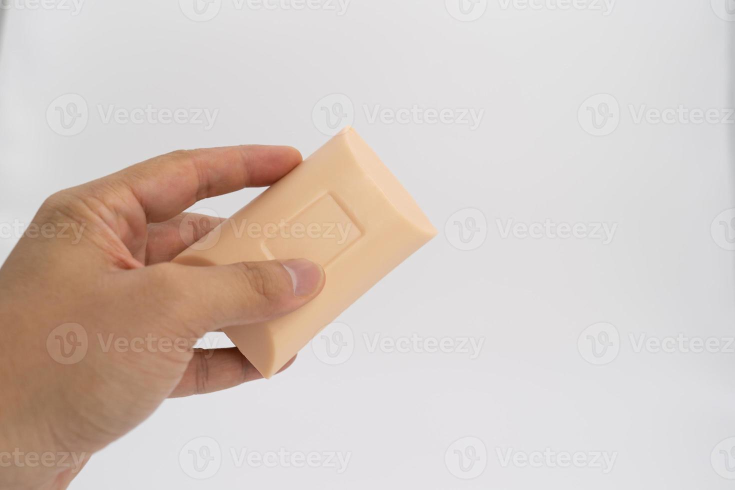 Asian mand hand holds rectangle cream color soap in studio light on white clear background. photo