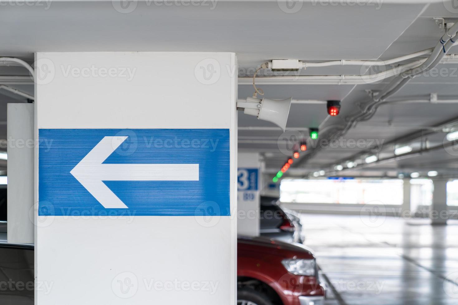 señalización de flecha blanca en el poste de estacionamiento interior, dígale al conductor qué camino tomar y ubicación en el estacionamiento. foto