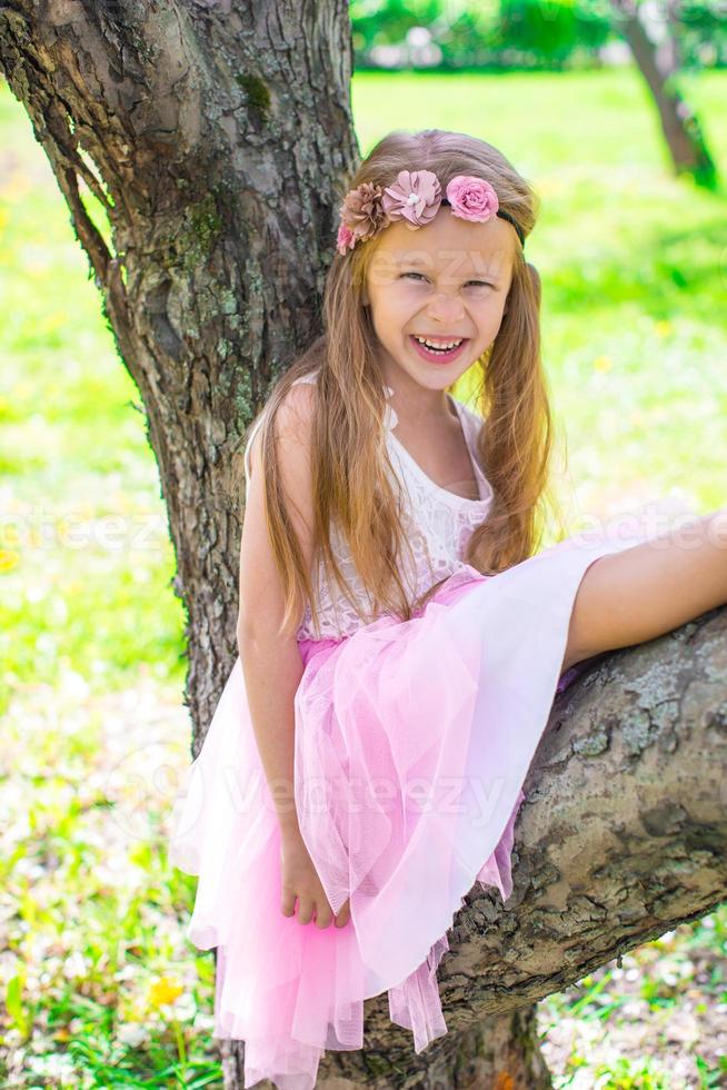 Happy little adorable girl in blossoming apple garden photo