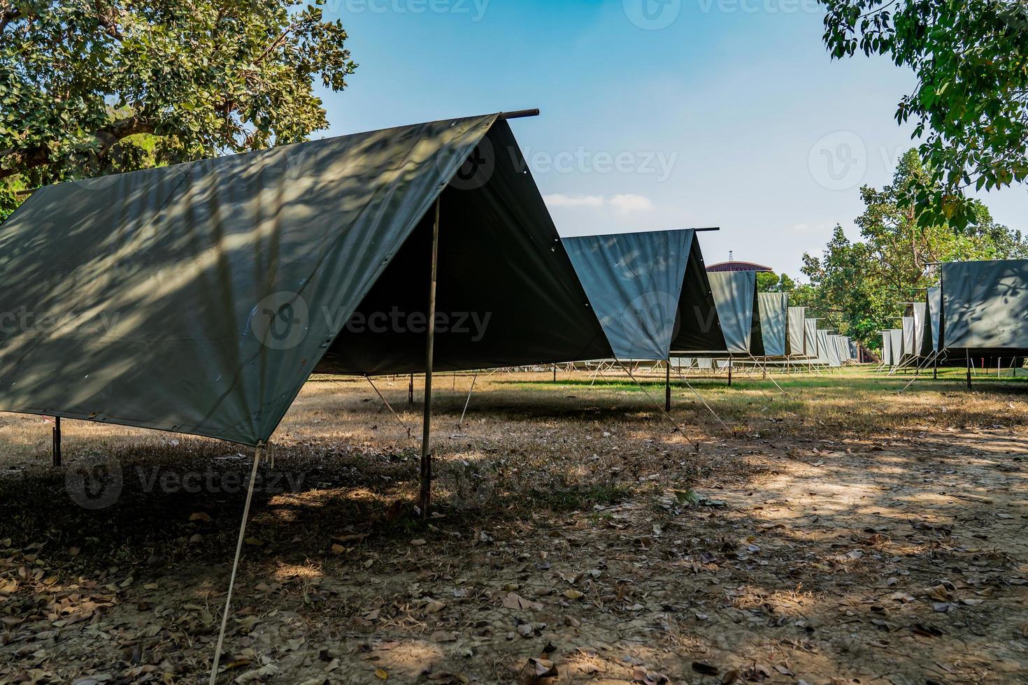 las tiendas de lona vacías simples y normales en la fila y la columna en el campo de hierba en el campo al aire libre en el tiempo de la tarde. foto