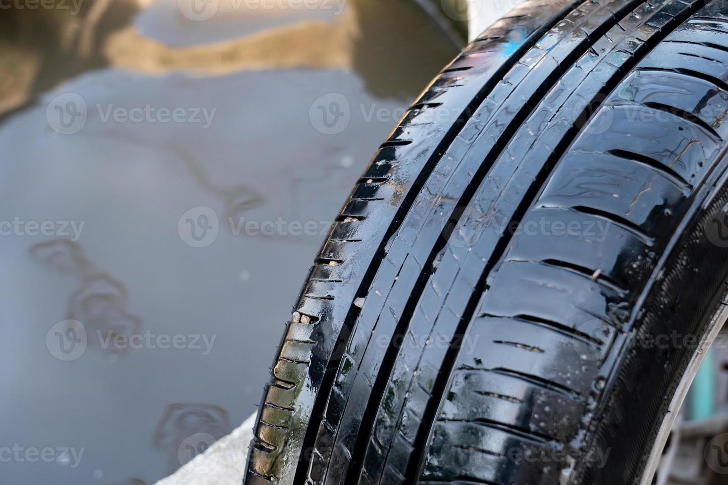 close up to the wet broken tire with the a small nail puncture on it. photo