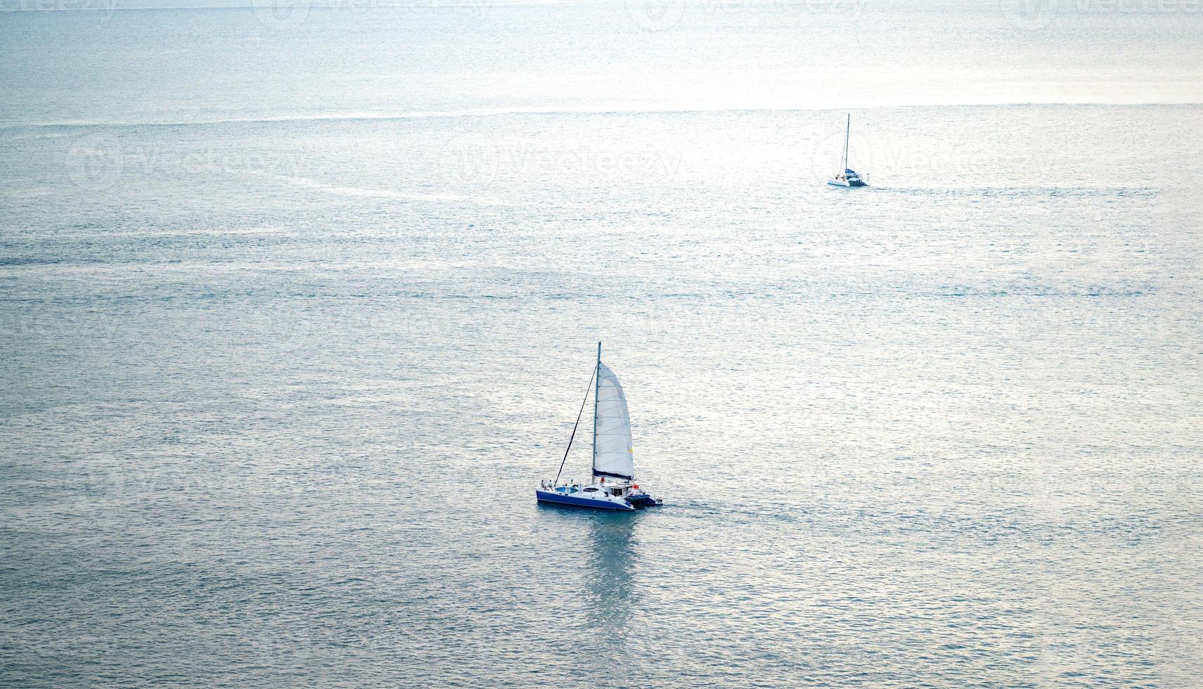 minimal Sailboat Yacht is saling on the calm sea, shoot this image from above of the mountain Phrom Thep Cape, Phuket Thailand with Tele lens. photo