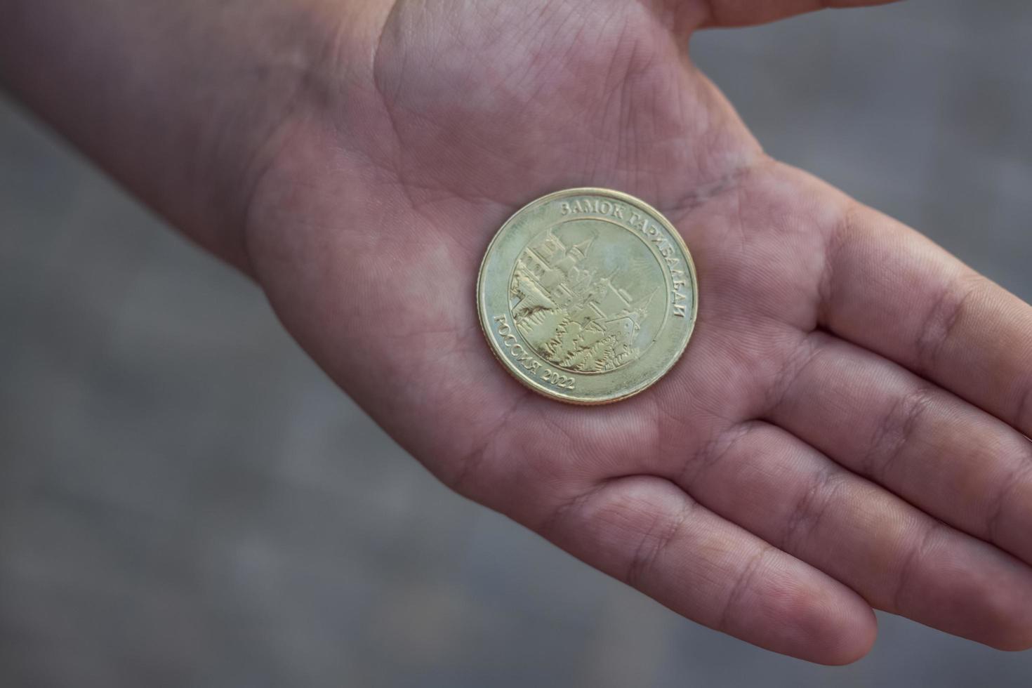 2022-08-16 Russia, Samara, Tourist center Castle Garibaldi in the village of Khryashchevka, Samara region. Newly minted commemorative coin in hand photo