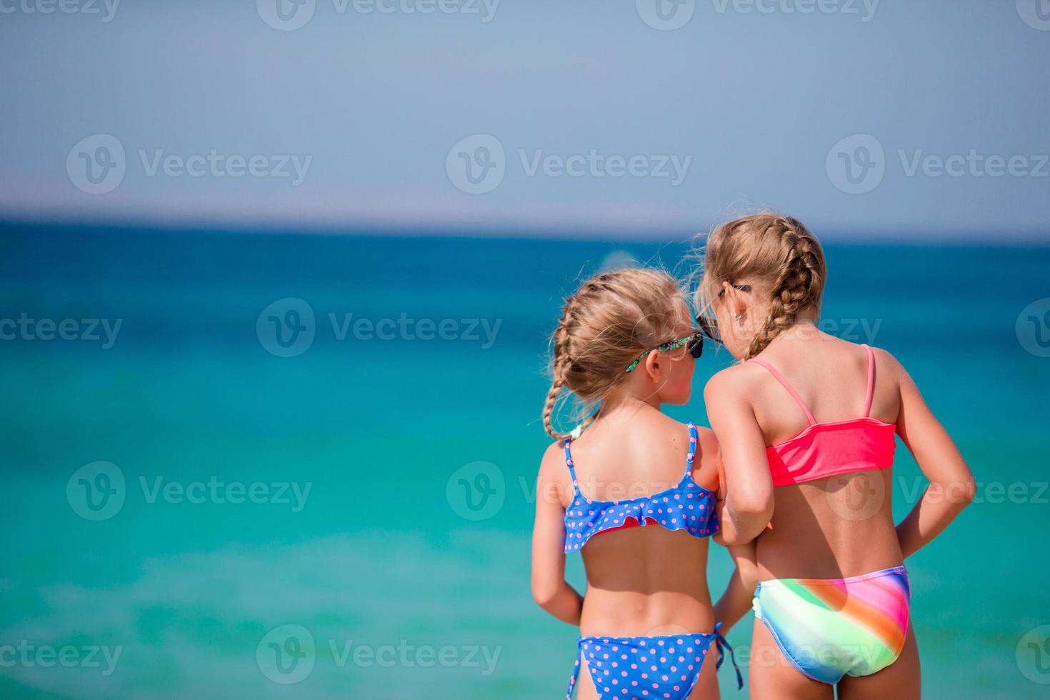 Adorable little girls having fun during beach vacation photo